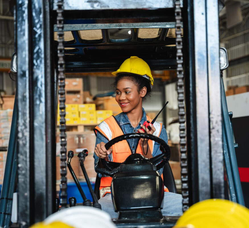 Portrait of a woman working with a forklift in a warehouse.